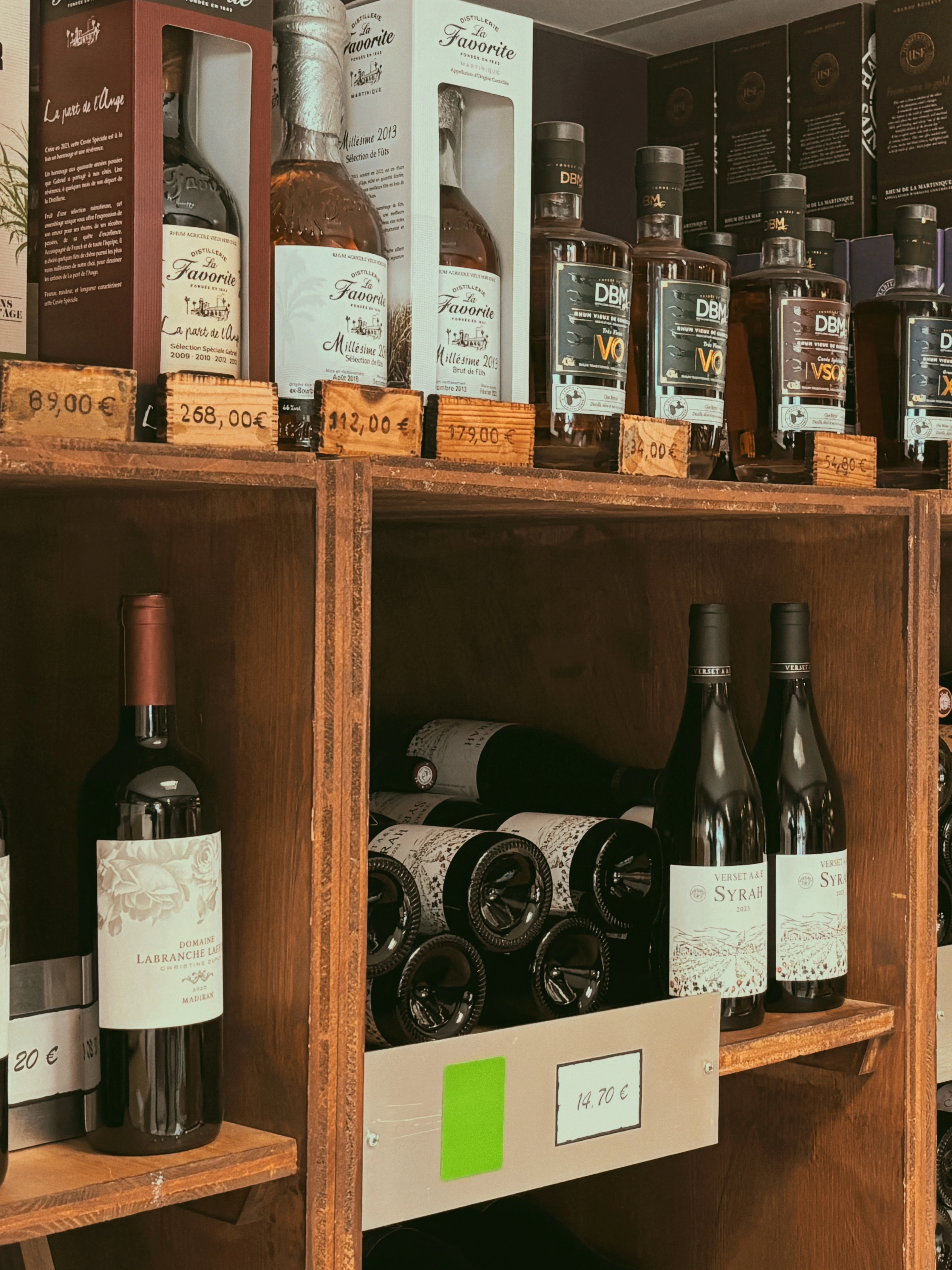 Étagères de la boutique As du Vin à Dijon présentant des bouteilles de vin rouge et une gamme de rhums